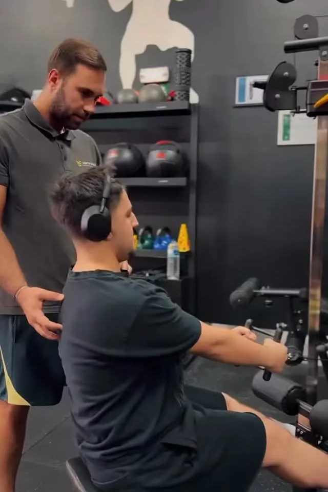 Personal trainer a corrigir a postura de um cliente num exercício de remada sentado